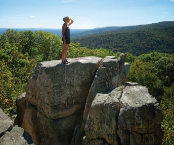 A hiker standing on top of Chimney Rock overlooking Frederick County.