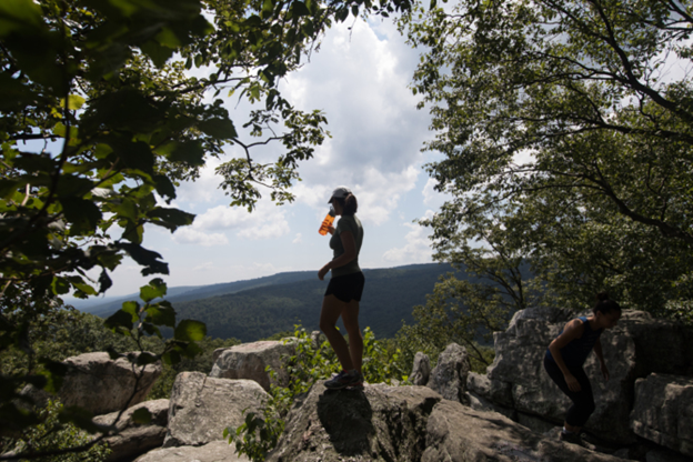 A hiker takes a water break at the top of Chimney Rock overlooking Frederick County.