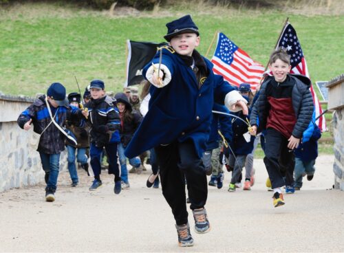 Image of children in Civil War costumes charging over a bridge