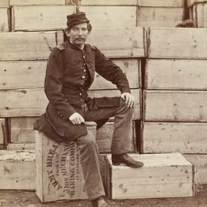 Civil War-era photo of a soldier sitting on top of a crate of rations