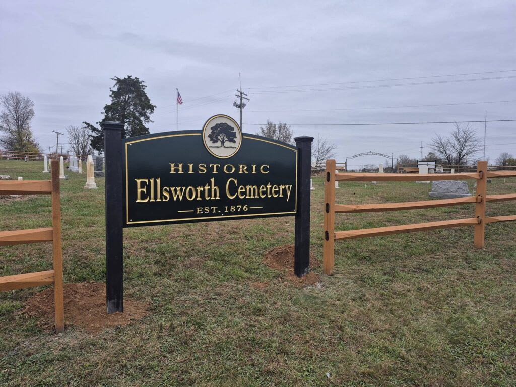 Large black sign with gold letters reading "Ellsworth Cemetery"