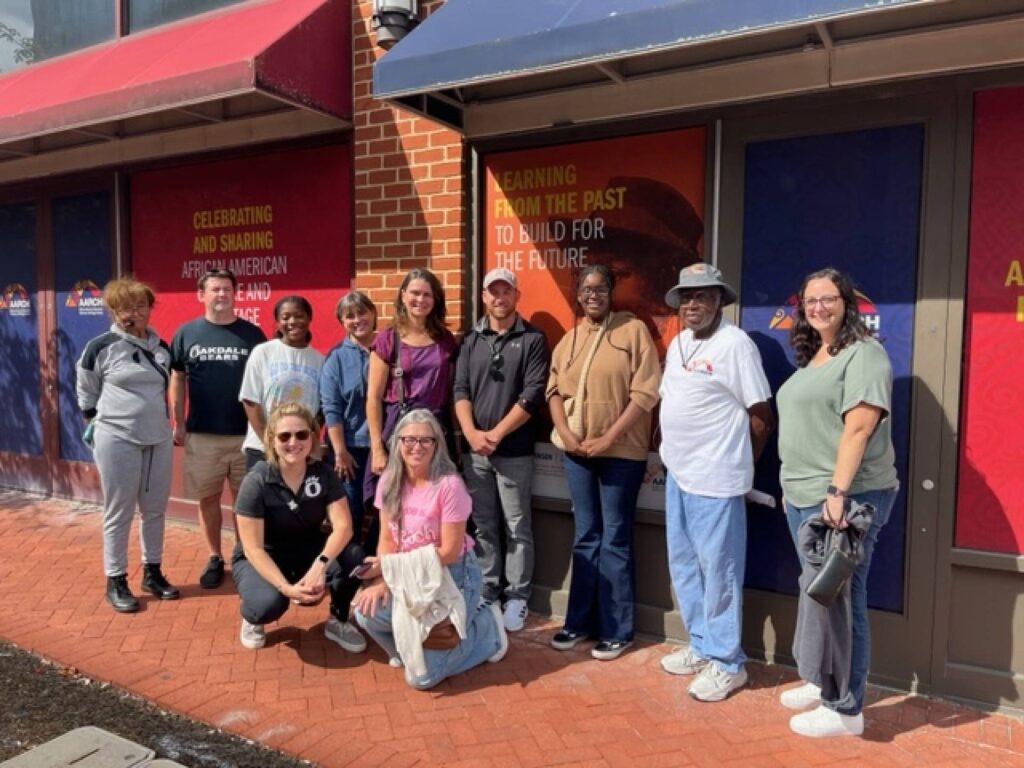 Approximately a dozen people stand in front of the AARCH Society African American Heritage Center.